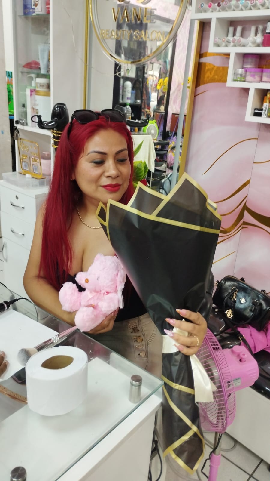 Clienta con su ramo en envoltorio negro y dorado y un peluche rosado de Munay