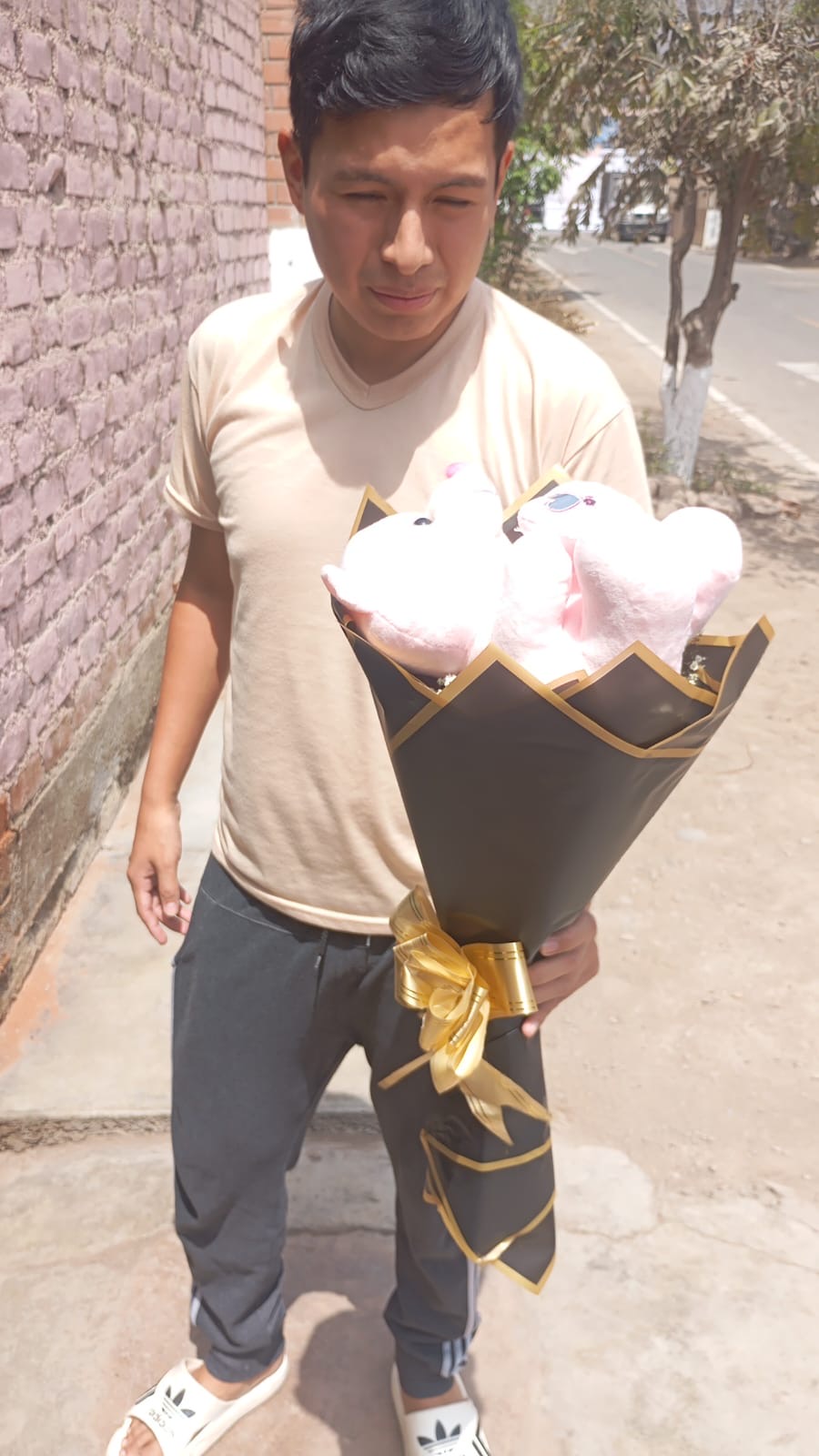 Cliente de Munay con un ramo de peluches rosados en envoltorio negro y dorado