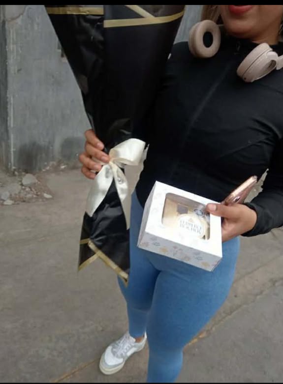 Clienta con su ramo Munay en envoltorio negro y dorado y una caja de chocolates